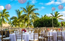 On a patio, paper lanterns are strung above tables set with floral centerpieces