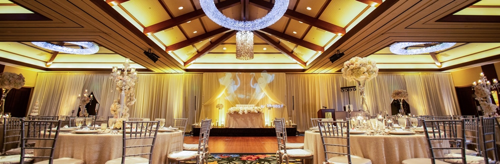 Round tables with elaborate floral centerpieces in a room with a dance floor