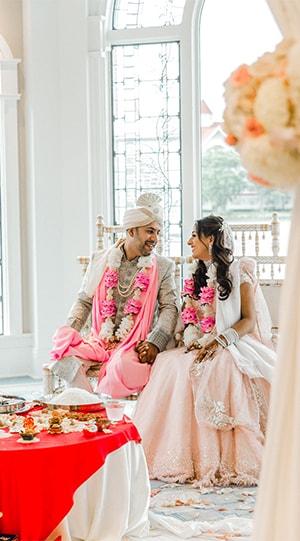 Couple dressed in traditional wedding attire smiling at each other