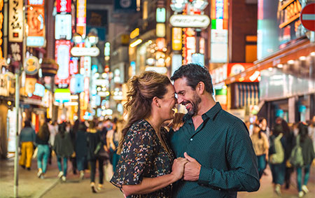 Newlyweds hugging amid city lights during their honeymoon in Tokyo, Japan