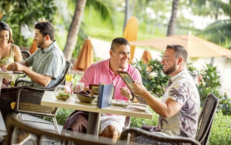 Two men check out the menu over a meal at Aulani A Disney Resort & Spa
