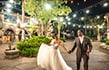 A newlywed bride and groom holding hands and smiling under string lights in front of India inspired architecture at Disney's Animal Kingdom theme park