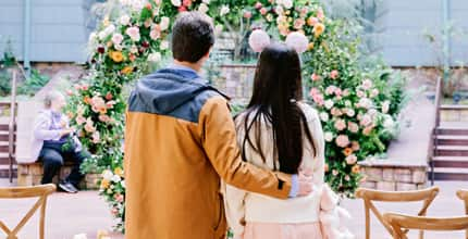 A newly engaged couple viewing a wedding arch adorned with flowers as they chose their wedding venue in Disneyland