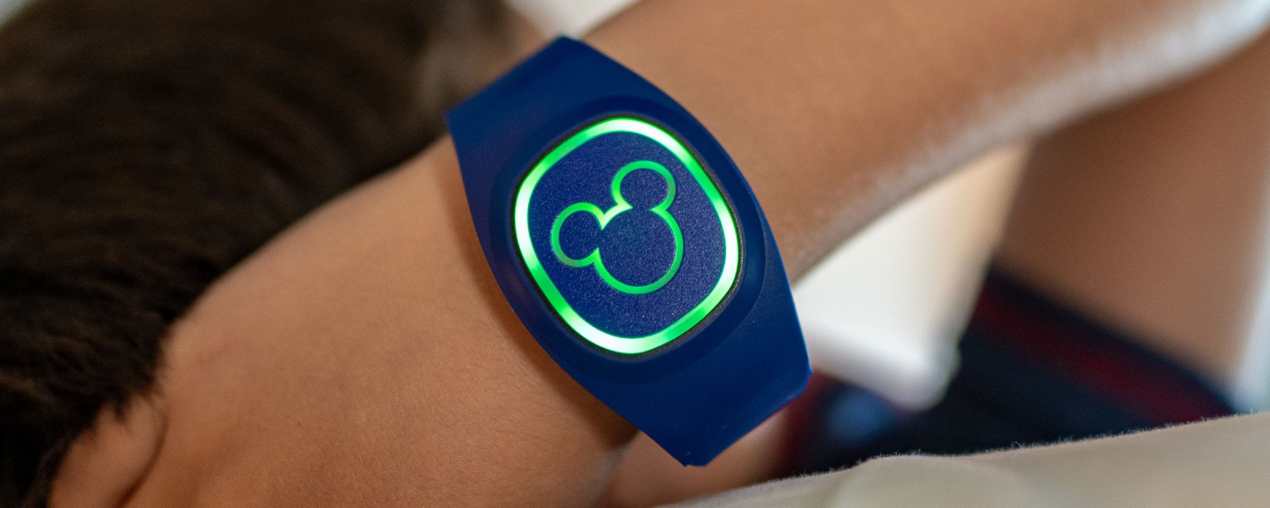 Many small circles encircling an icon of a Mickey Mouse head, with text that reads MagicBand plus