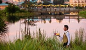 A Cast member carrying a tray of drinks outdoors by the water