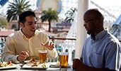 Men seated at an outdoor table with glasses of beer and plates of food Men seated at an outdoor table with glasses of beer and plates of food