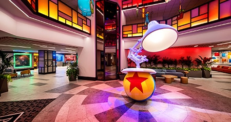 A hotel lobby with a large Luxo Jr lamp and Pixar ball sculpture, stained glass panels and other Pixar character decoration