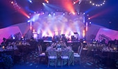 The Great Hall with elegantly set tables, a stage and colorful lighting