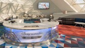 Test A room with modern décor, and check–in desk with a sign reading "Disney Vacation Club Member Lounge"