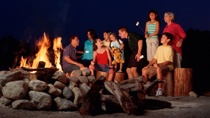Families gathered around a campfire, singing and roasting marshmallows