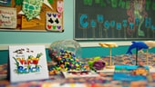 A crafts table filled with paints, brushes and Mickey-shaped plates