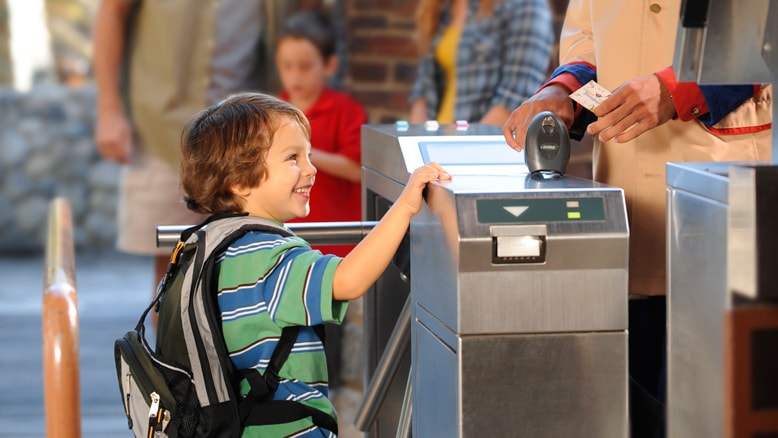 A young boy has his ticket scanned at a Disneyland Resort park turnstile