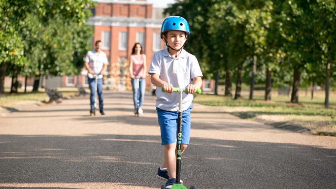 A family riding scooters along a paved pathway in London
