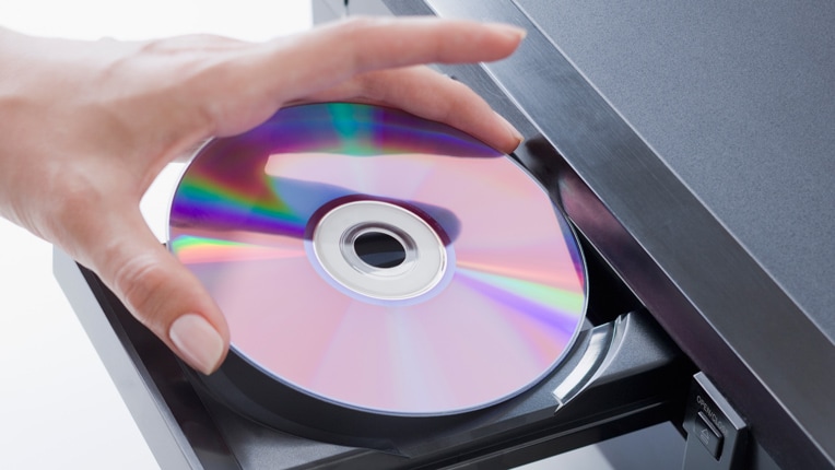 DVD プレーヤーに DVD を挿入する女性の手