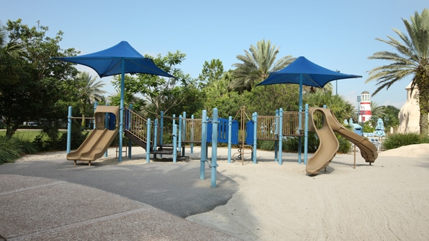 A playground on sand with slides and umbrellas