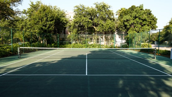 A tennis court with trees beyond