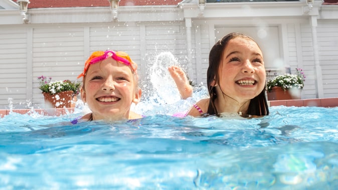 Two girls swim in a pool on a sunny day