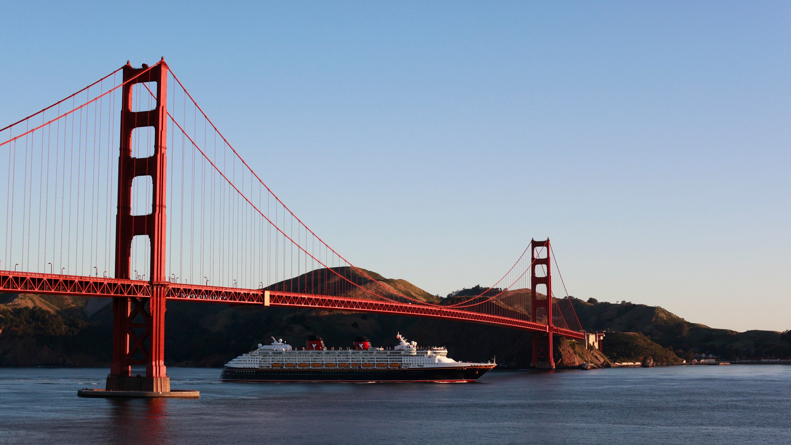 The Disney Wonder cruise ship sailing beneath the Golden Gate Bridge