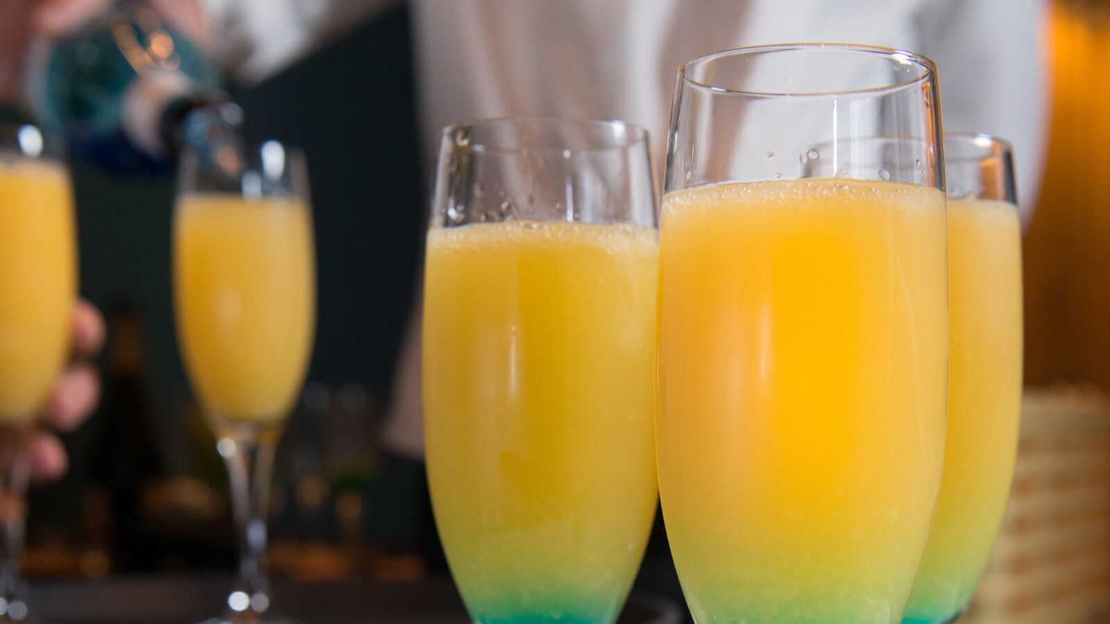 Several mimosas and a server pouring another mimosa