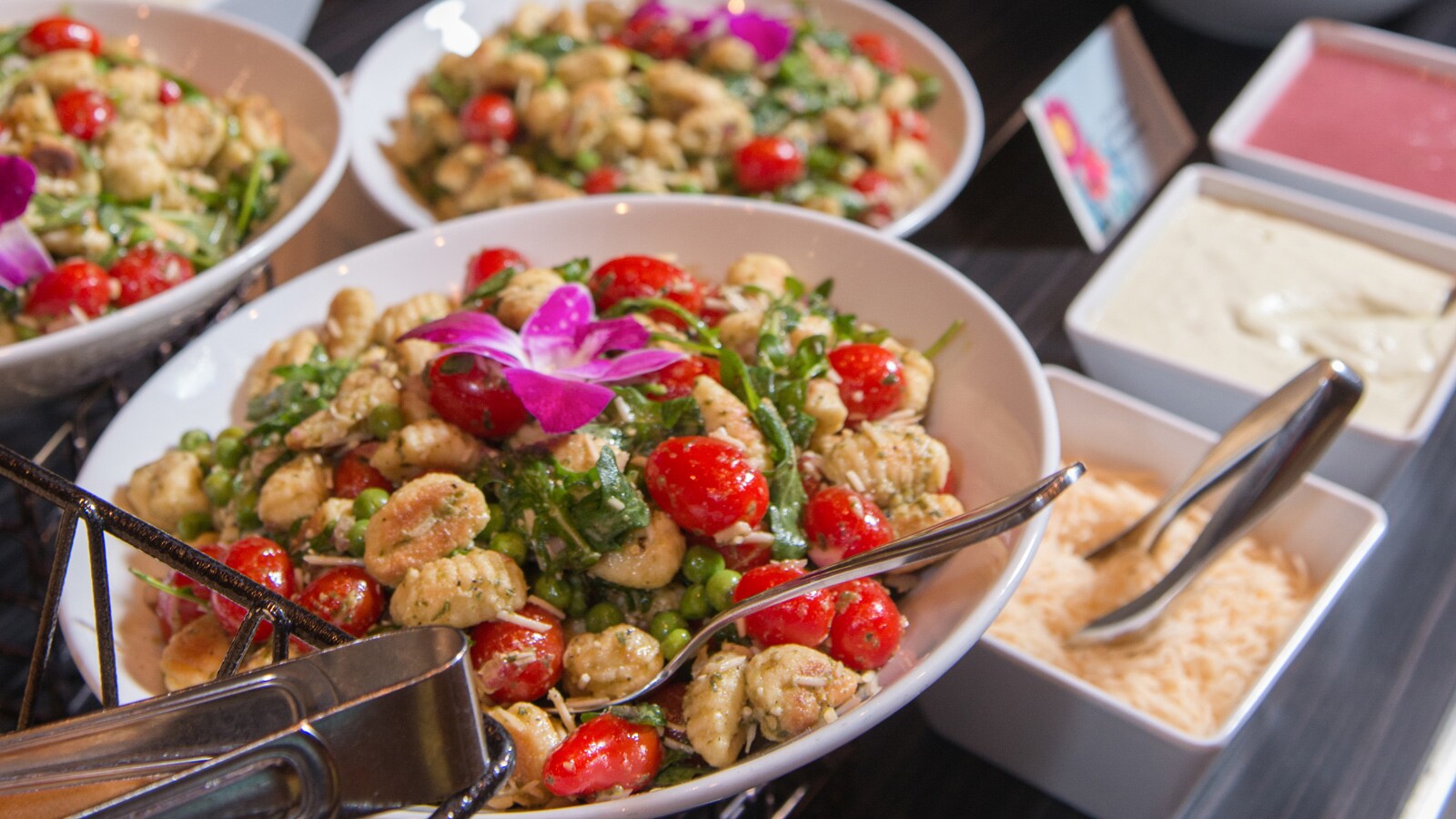 A buffet table with plates of assorted salads and bowls of salad dressing