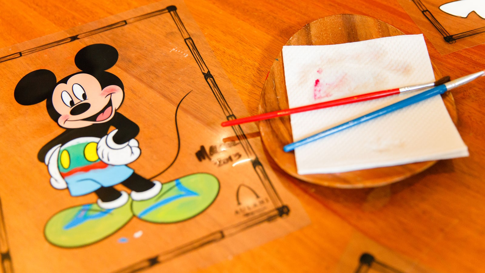 A Mickey Mouse design beside 2 paint brushes