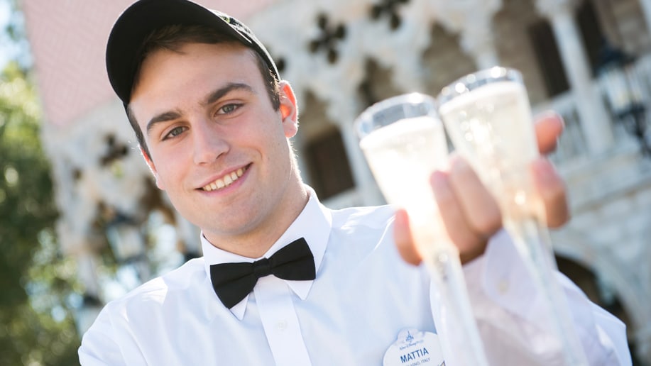 A Cast Member holding 2 glasses of sparkling wine