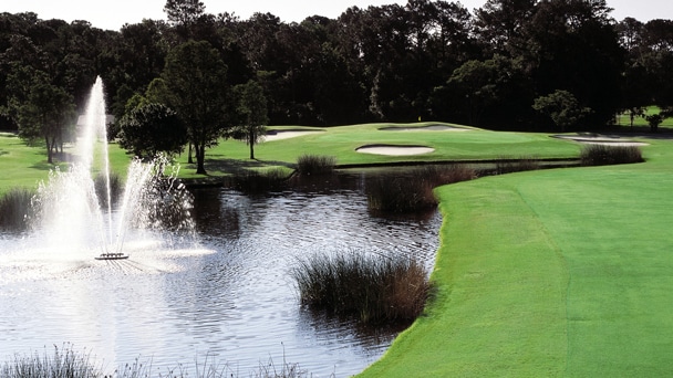 A small lake and fountain on a golf course