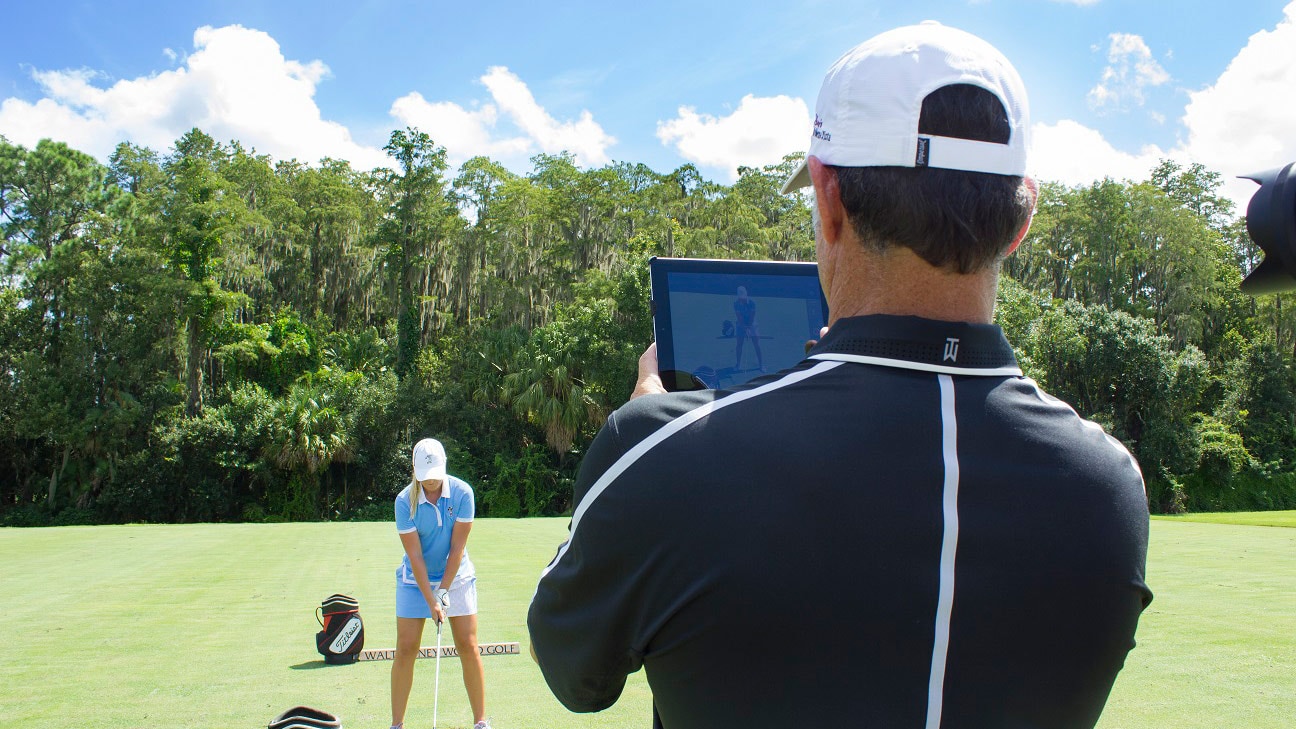A golf pro takes a photo of a student golfer