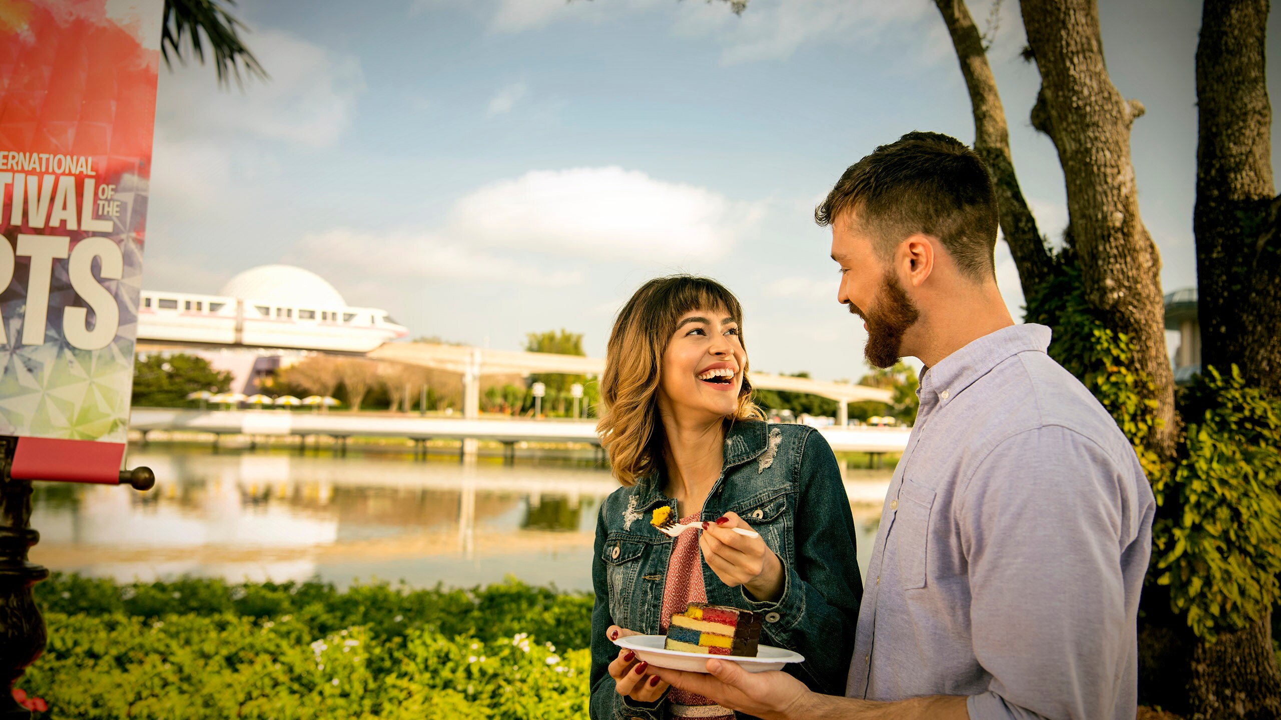 A smiling couple share a plate of cake near the World Showcase Lagoon