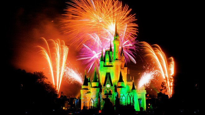 Fireworks illuminate the night sky behind Cinderella Castle