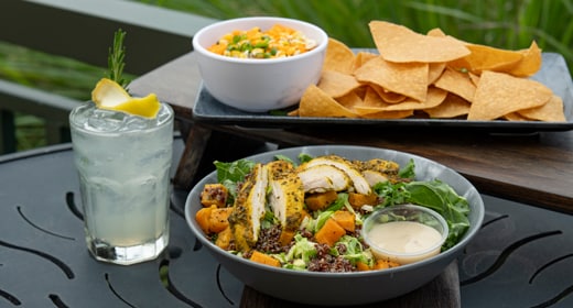 A table set with a salad, vegetables, snacks and a lemon drink