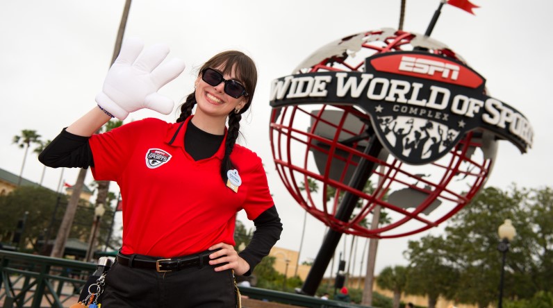 A Disney Cast Member wearing a Mickey Mouse glove and waving hello outside of the ESPN Wide World of Sports Complex