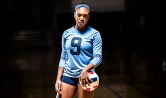 A volleyball player in a number-9 jersey and shorts holds a volleyball against her side
