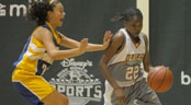 AAU Girls' Basketball A teenage female basketball player dribbles with her left-hand around a defender