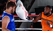 One man being hit in the face with a pillow by another man.