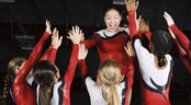 AAU Age Group Level Gymnastics National Championship A team of young female gymnasts celebrate with a group high-five