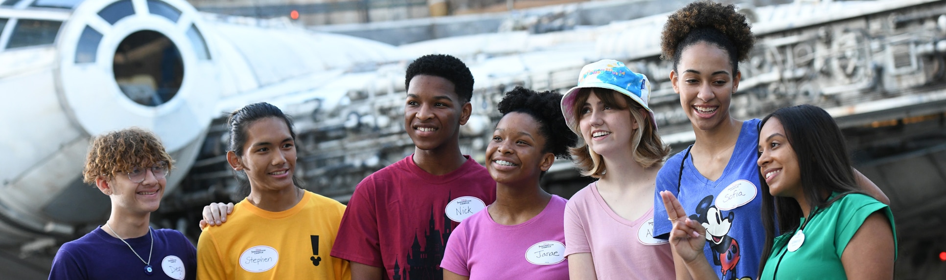 7 Disney Imagination Campus students stand in front of the Millennium Falcon in Star Wars Galaxy’s Edge