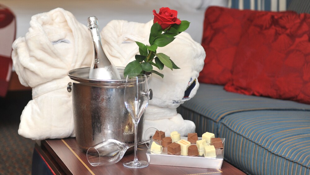 A box of chocolates, 2 bath robes and 2 glasses next to an ice bucket with a rose and a bottle of Champagne
