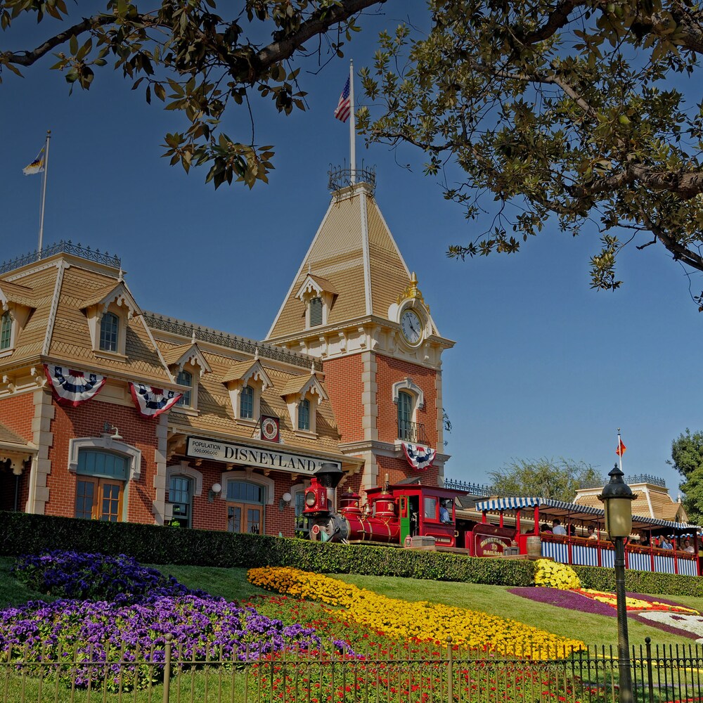 A train filled with people pulls into the station at Disneyland Park