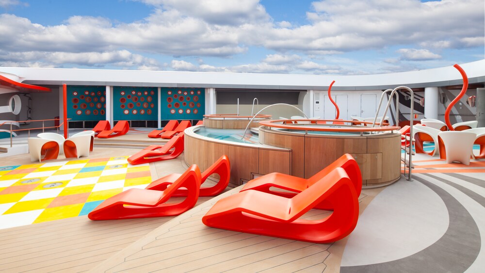 Cubierta del club Vibe con sillas de estilo moderno, camastros, piscinas y un tablero de ajedrez gigante