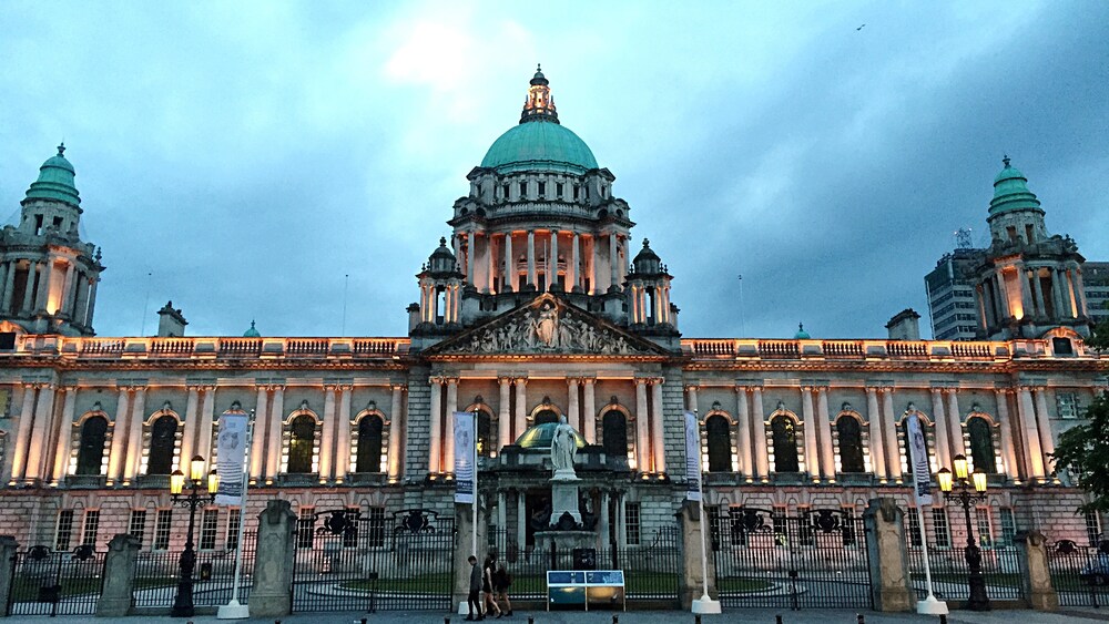 People walk near a large building with a statue in front of it