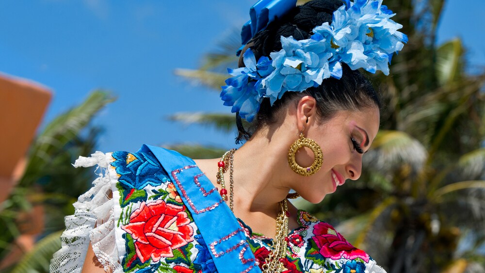 Profile of a woman with a headdress of flowers, flashy jewelry and other traditional festive garb on