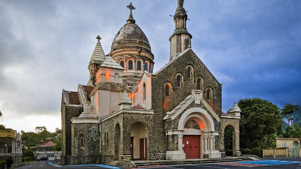 An old stone church with 2 spires and a large domed steeple