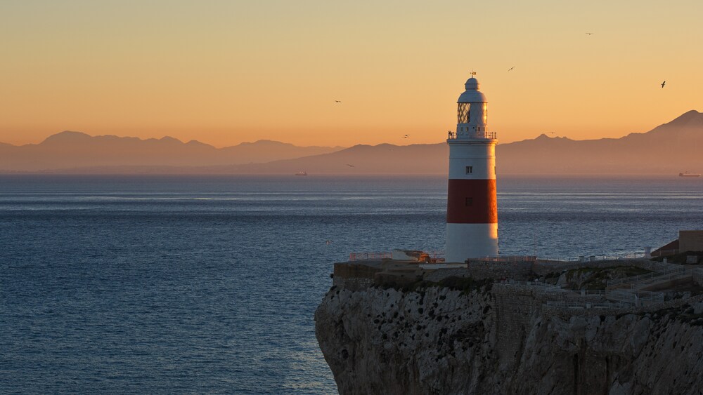 A lighthouse on a rocky cliff overlooking the ocean