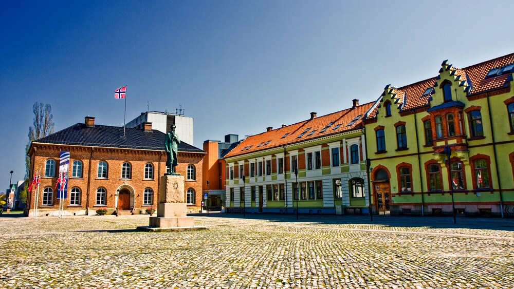 Brick 2 story buildings with surround a cobblestone plaze with a statue in the center