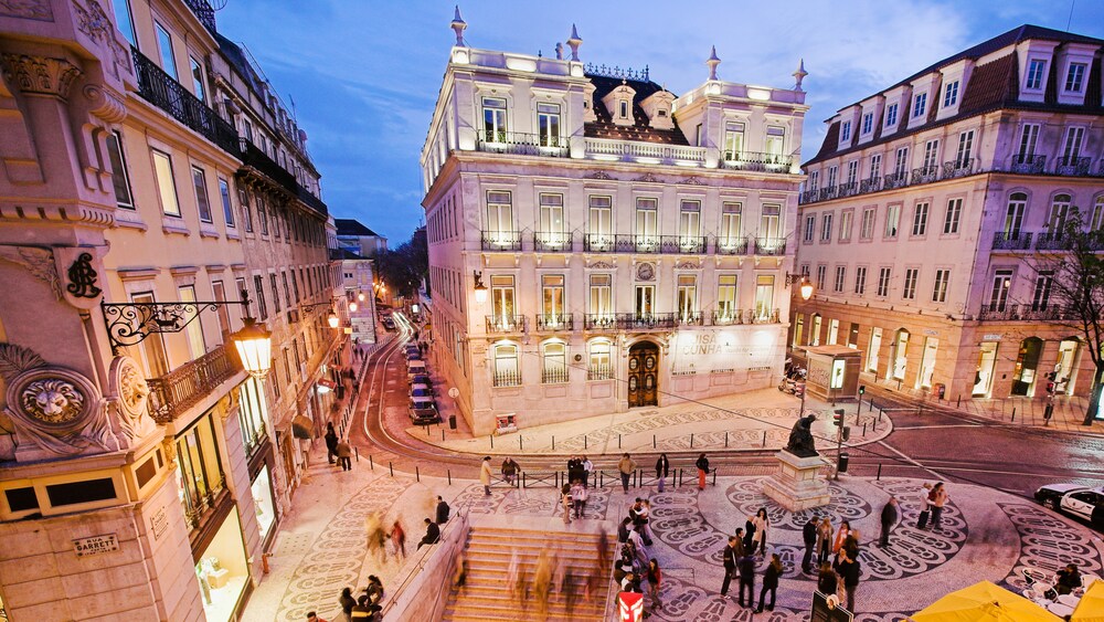 Baroque style buildings, amid busy streets with people and cars at night