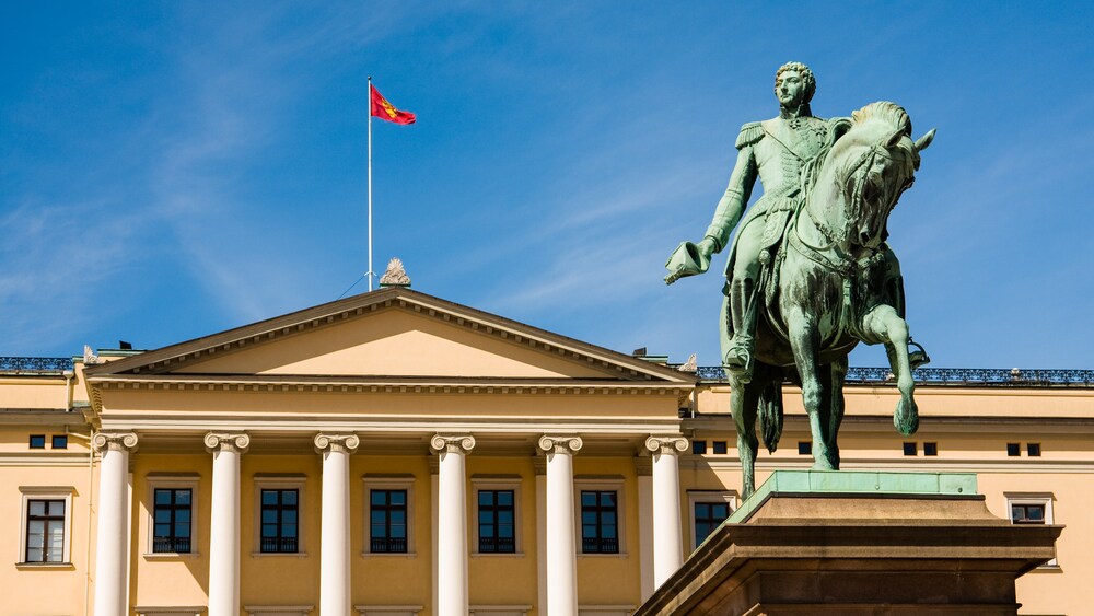 Statue of a man riding horseback in mililarty garb infront of large building with pillars