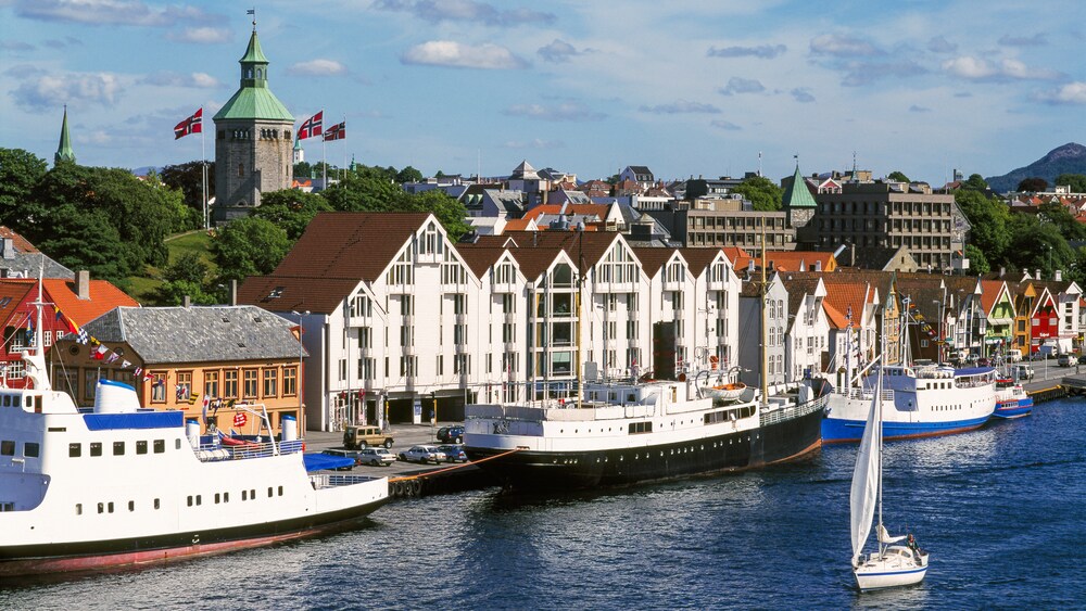 Ships moored in front of a row of builidings sitting side by side with pointed roofs