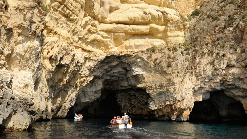 Two small motor boats heading into a large cave