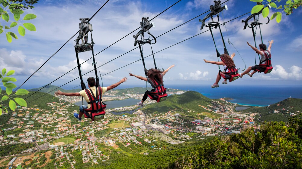 Cuatro personas amarradas a arneses en las tirolesas ubicadas sobre una isla boscosa